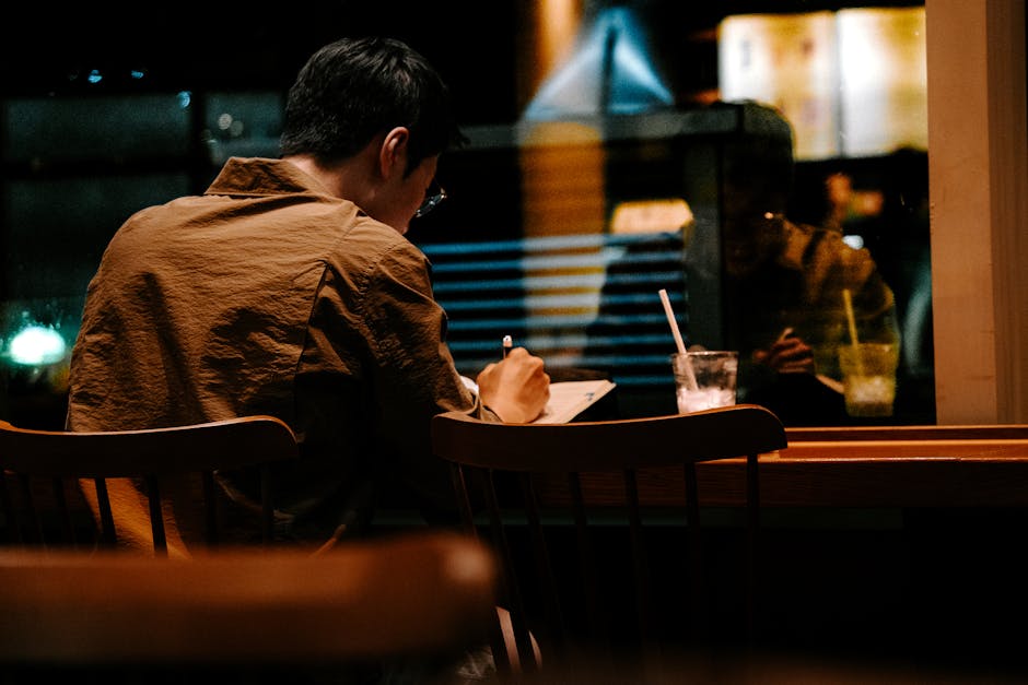 男性がカフェで会話のメモを書いて準備している