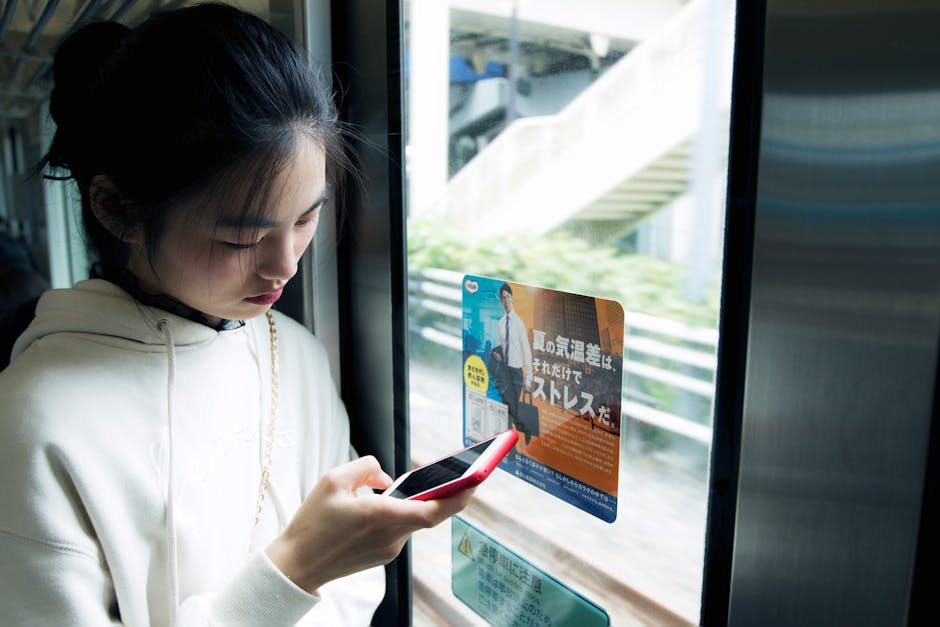 電車でスマホを見て微笑む女性
