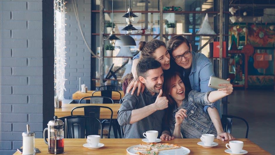 Young friends laughing together over brunch on an outdoor terrace