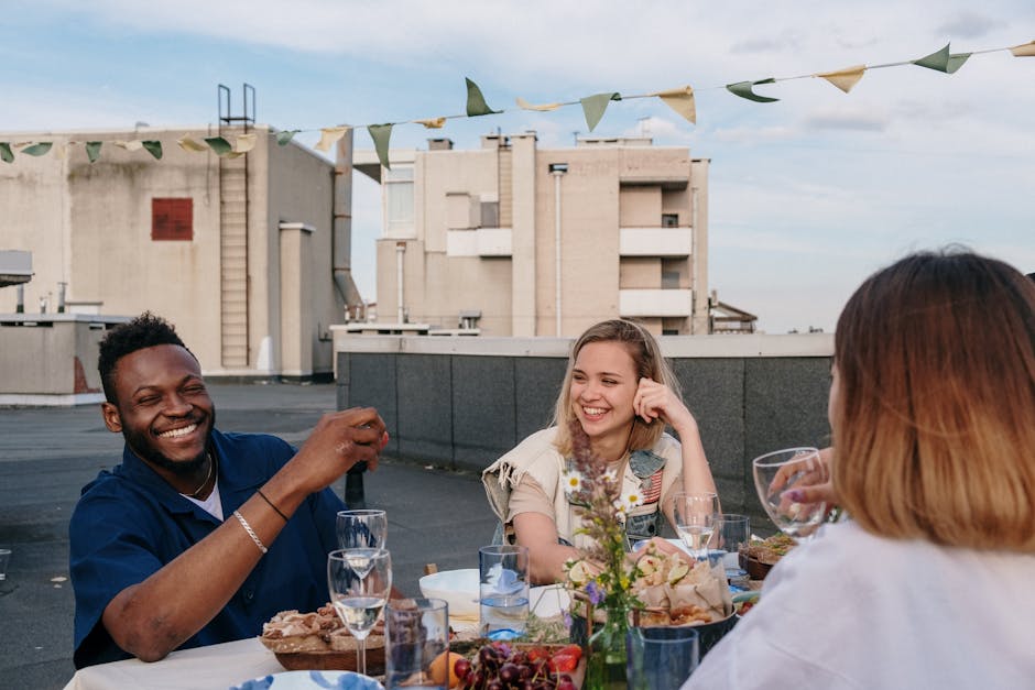 Diverse friends smiling during brunch on a sunny outdoor terrace