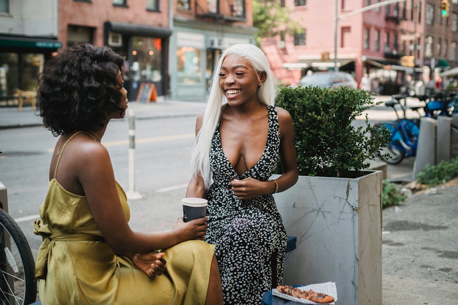 Two women talk beside a window table in an urban cafe.
