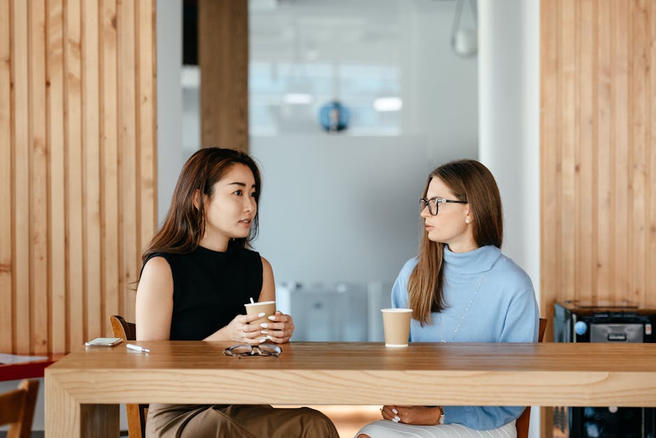 Young colleagues chatting casually beside laptops in a bright coworking space