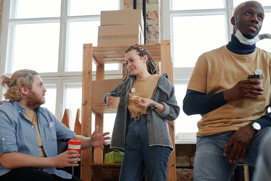 Young colleagues chatting casually in a bright coworking space with laptops nearby