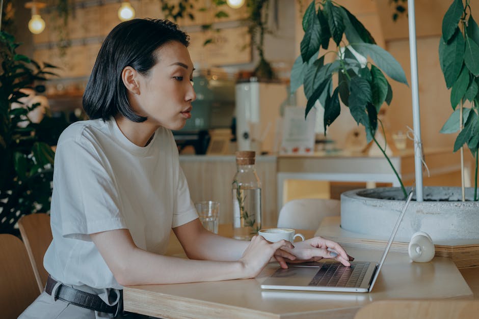 Woman smiling while working on a laptop in a modern coffee shop