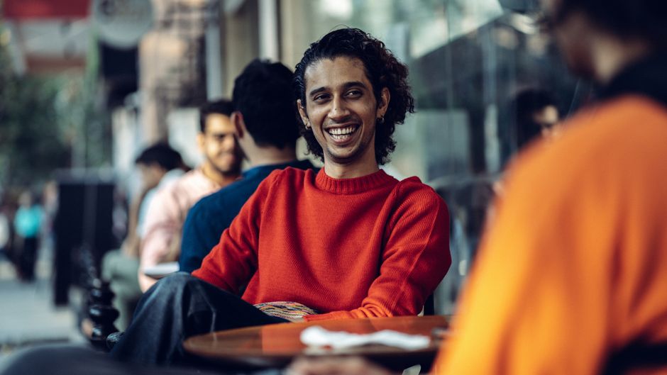 Young man smiling in a coffee shop while waiting for a casual social meetup