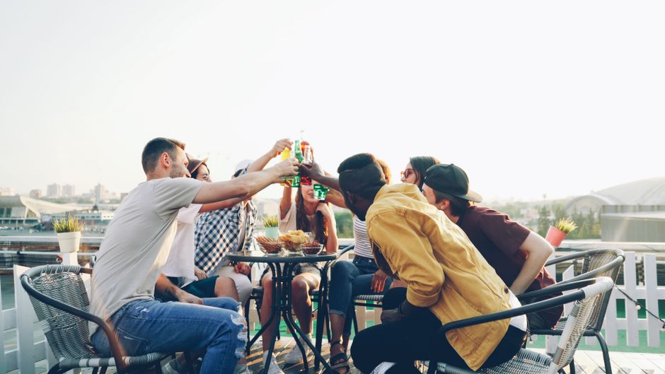 Friends smiling at an outdoor brunch terrace during a comfortable group conversation