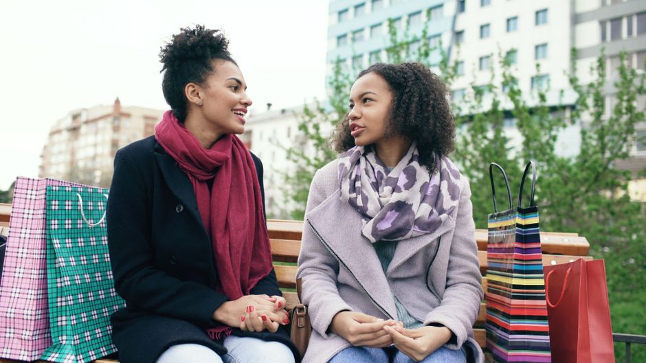 Two friends talking while walking along a green park pathway