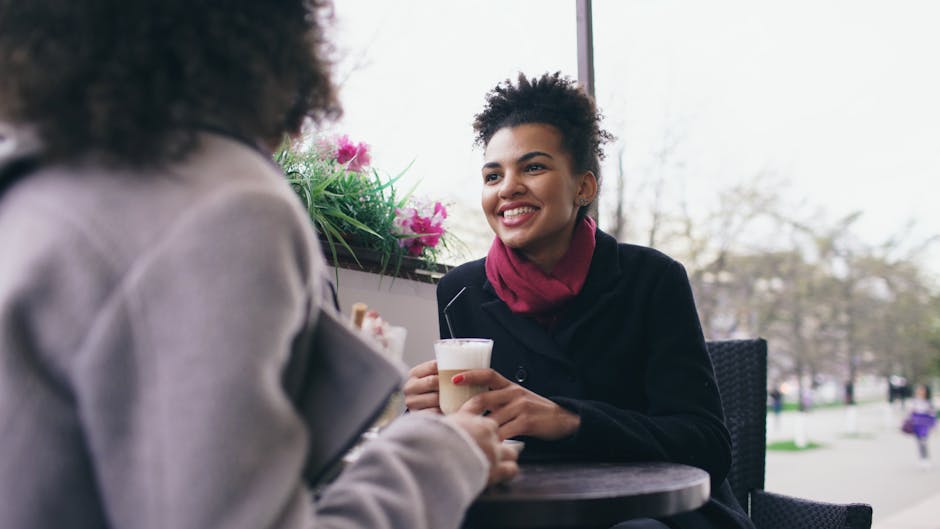 Two women talking warmly across a small cafe table