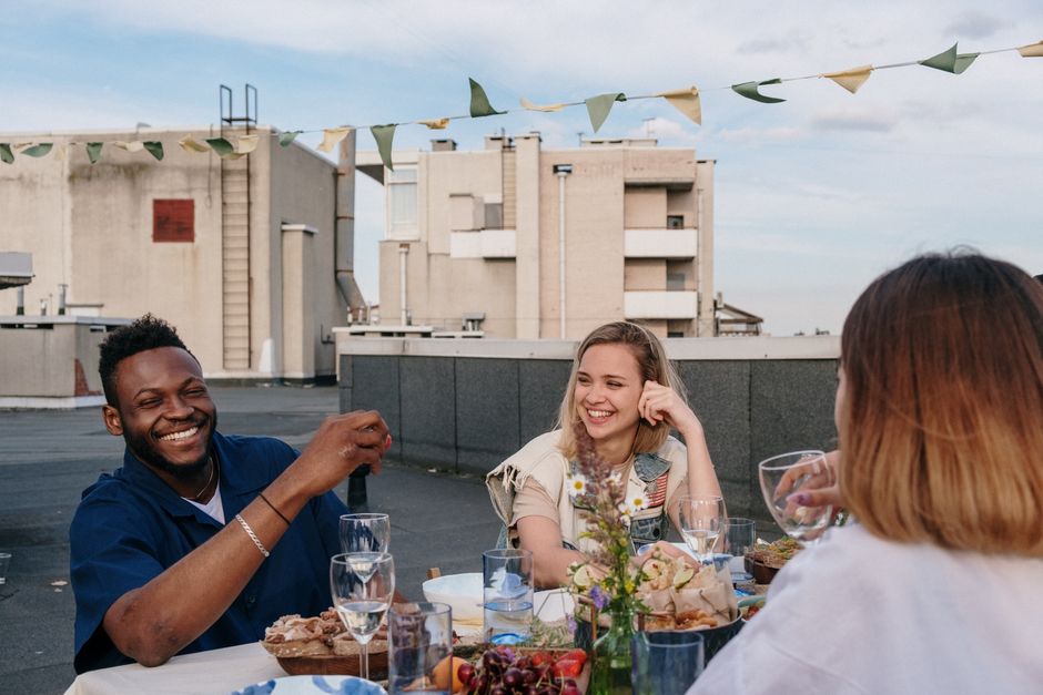 Young friends laugh together during brunch on an outdoor terrace
