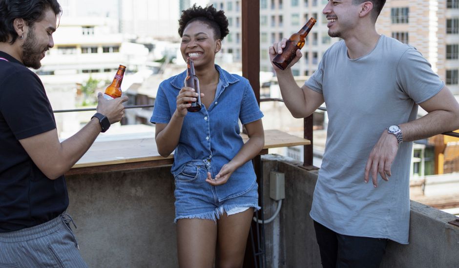 Young friends laughing during brunch on a sunny outdoor terrace