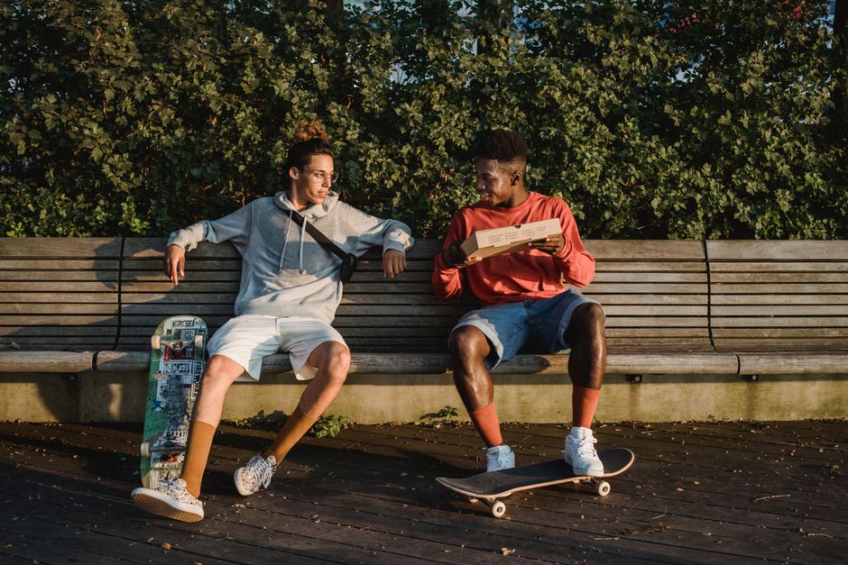 Young friends smiling during a relaxed conversation on a park bench