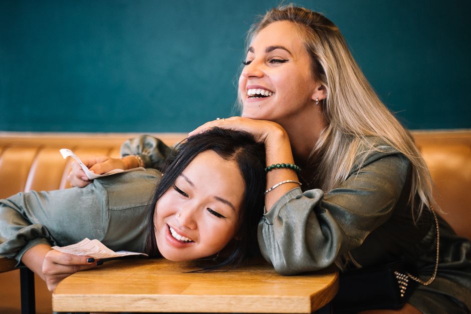 Young friends laughing together at a busy coffee shop table