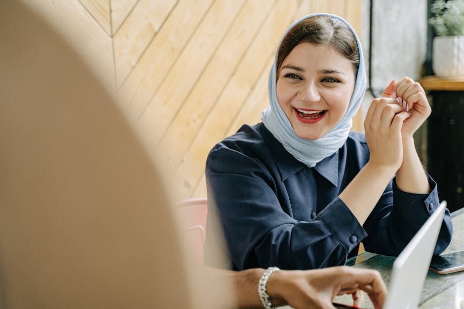 Woman smiling while working on a laptop in a coffee shop