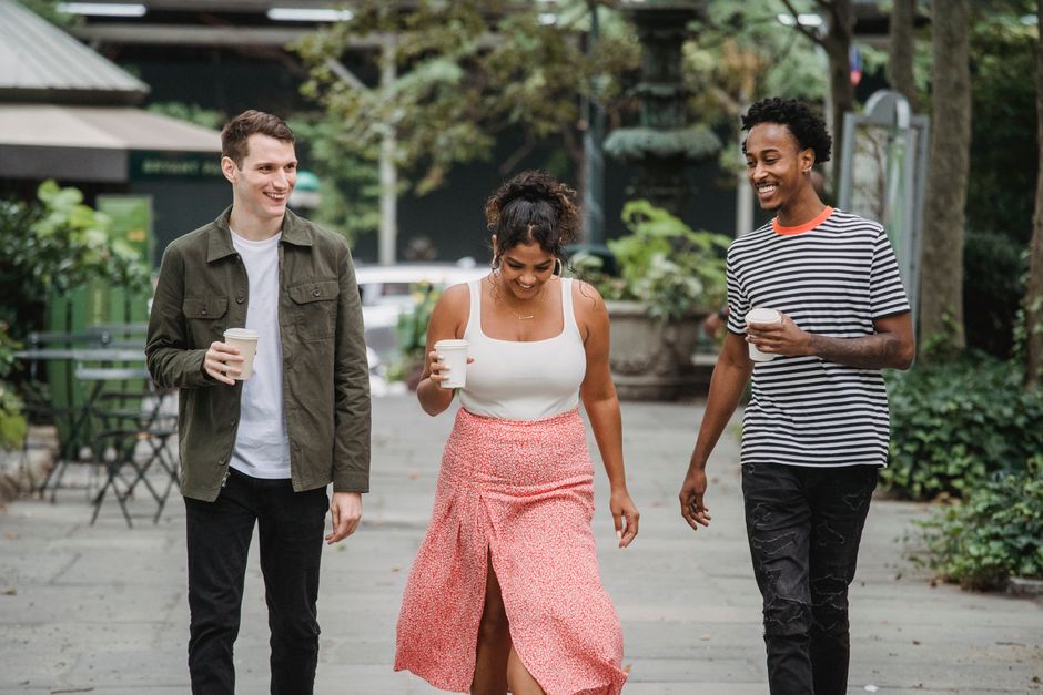 Friends smiling while walking through an urban park after meeting at brunch