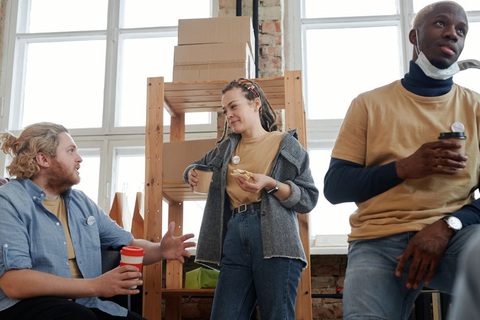 Young colleagues chat casually beside laptops in a coworking space