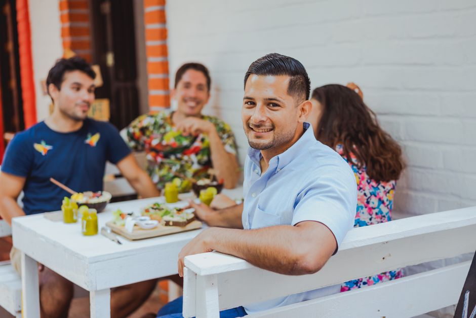 Young adults smiling and talking together on an outdoor brunch terrace
