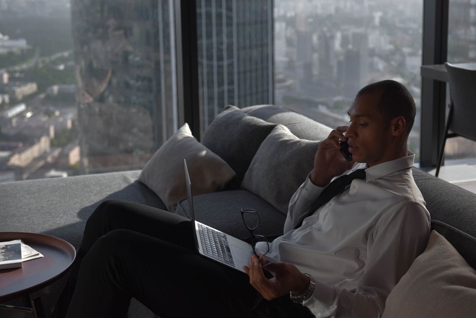 A young man resting on a couch while looking at his phone indoors