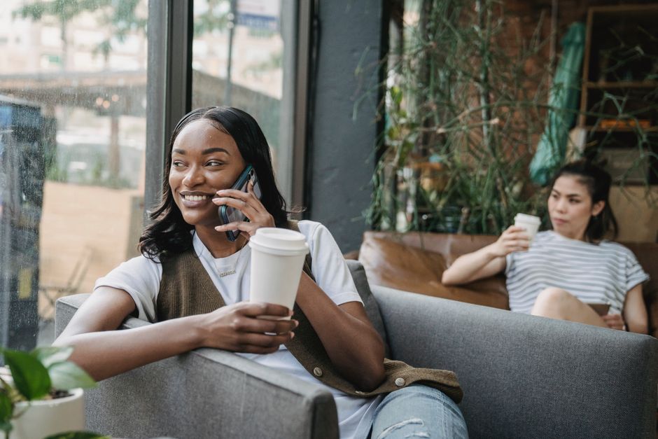 Woman checking her phone near a cafe window before leaving a city meetup